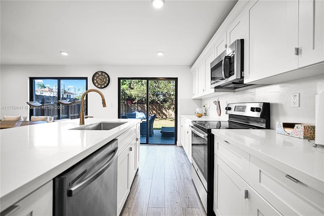 kitchen with light countertops, appliances with stainless steel finishes, a sink, and white cabinetry