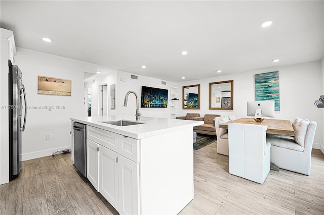 kitchen featuring stainless steel appliances, light wood-type flooring, white cabinets, and a sink