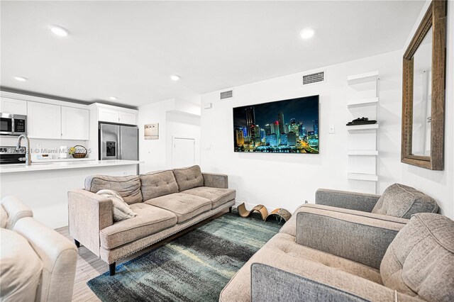 living room with light wood-type flooring, visible vents, and recessed lighting