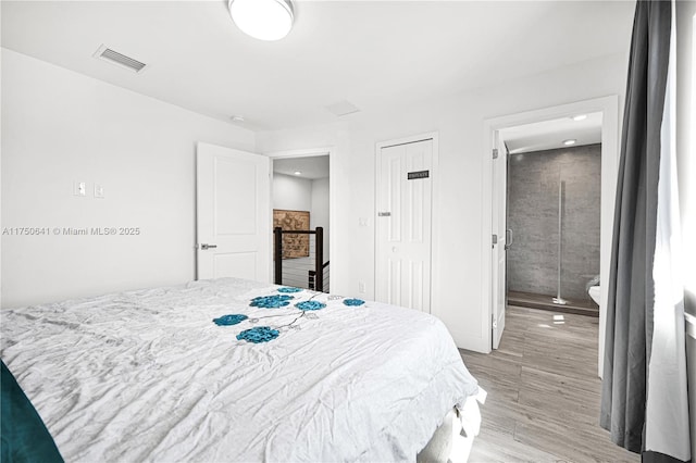 bedroom featuring light wood-style floors, visible vents, and ensuite bath