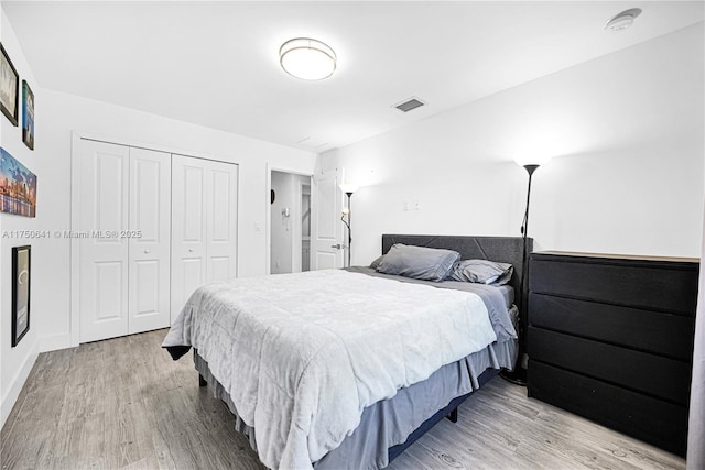 bedroom with light wood finished floors, a closet, and visible vents