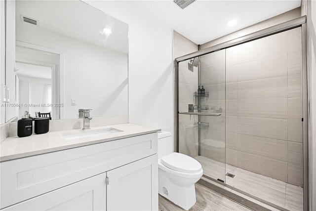 full bathroom with toilet, a shower stall, visible vents, and wood finished floors