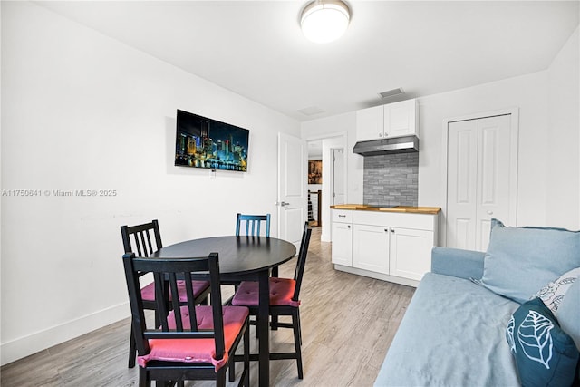 dining space featuring visible vents, light wood-style flooring, and baseboards