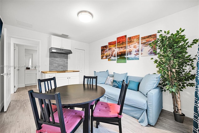 dining space with baseboards, visible vents, and light wood finished floors