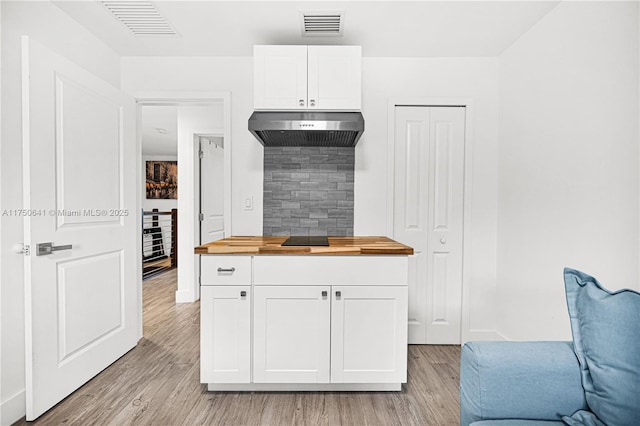 kitchen featuring white cabinets, visible vents, wooden counters, and under cabinet range hood