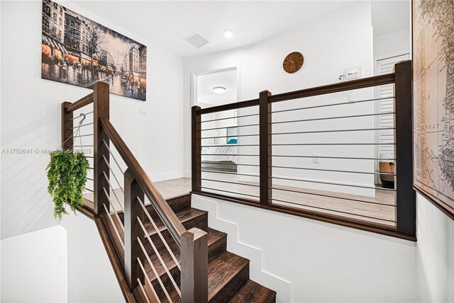 staircase featuring visible vents and wood finished floors