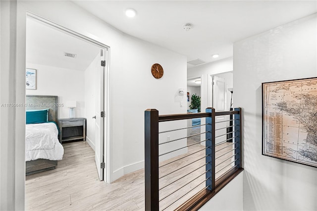 hallway featuring recessed lighting, visible vents, light wood-style flooring, an upstairs landing, and baseboards