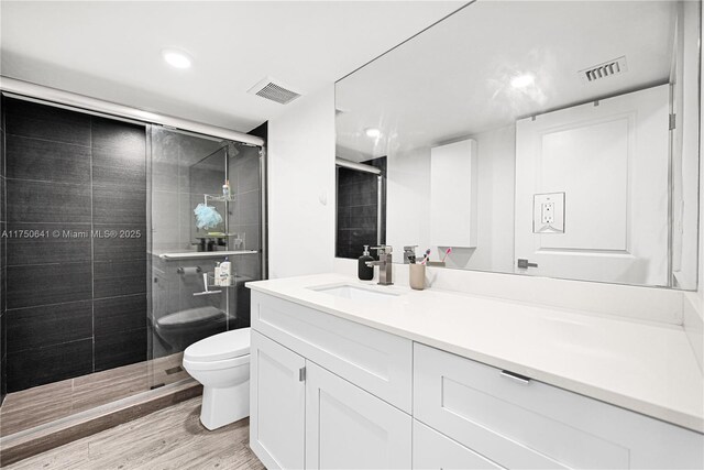 full bathroom featuring a stall shower, visible vents, toilet, and wood finished floors