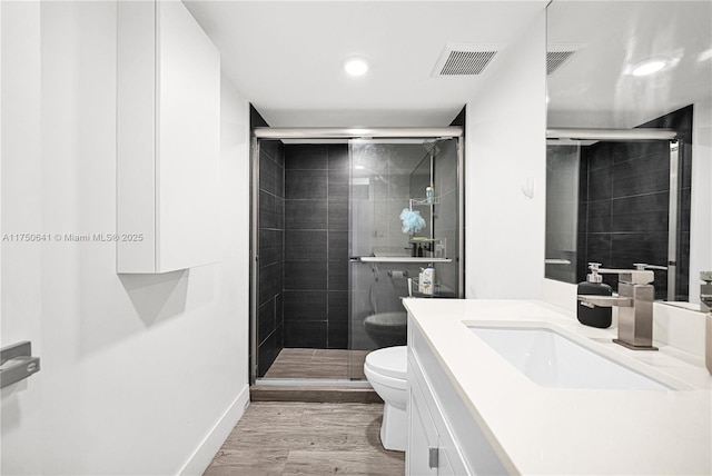 bathroom with visible vents, toilet, wood finished floors, vanity, and a shower stall