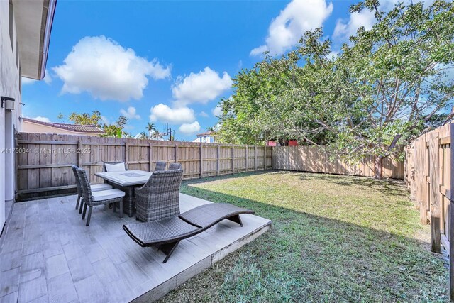 view of yard with outdoor dining space, a fenced backyard, and a patio