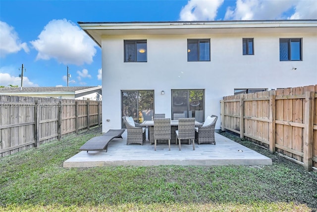 back of house featuring a yard, a fenced backyard, a patio, and stucco siding