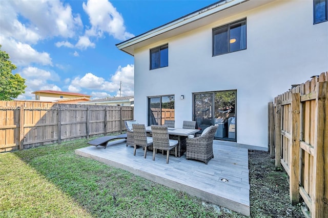 rear view of property featuring outdoor dining space, a fenced backyard, a yard, and stucco siding