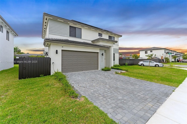 traditional home with a garage, a lawn, fence, decorative driveway, and stucco siding