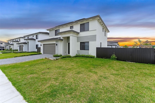 view of front of home with an attached garage, fence, decorative driveway, stucco siding, and a front yard