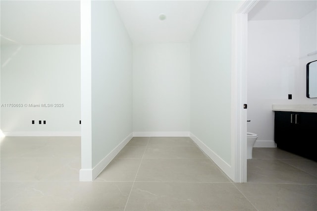 hall with light tile patterned flooring and baseboards