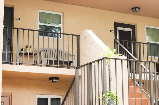 view of exterior entry with a balcony and stucco siding