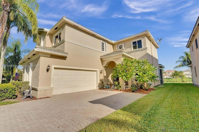 mediterranean / spanish-style house with a garage, a tiled roof, decorative driveway, stucco siding, and a front lawn