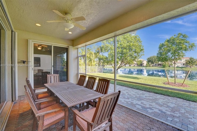 sunroom / solarium with a water view and ceiling fan