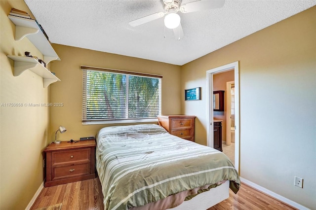 bedroom featuring a textured ceiling, a ceiling fan, light wood-style flooring, and baseboards