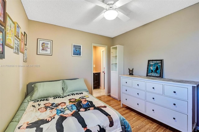 bedroom with a textured ceiling, ensuite bathroom, a ceiling fan, and light wood-style floors