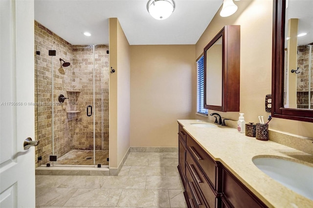 full bath with double vanity, a stall shower, a sink, and baseboards