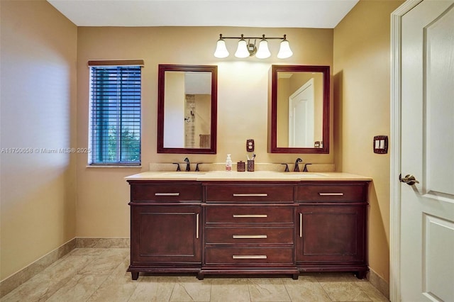 full bath featuring double vanity, a sink, and baseboards