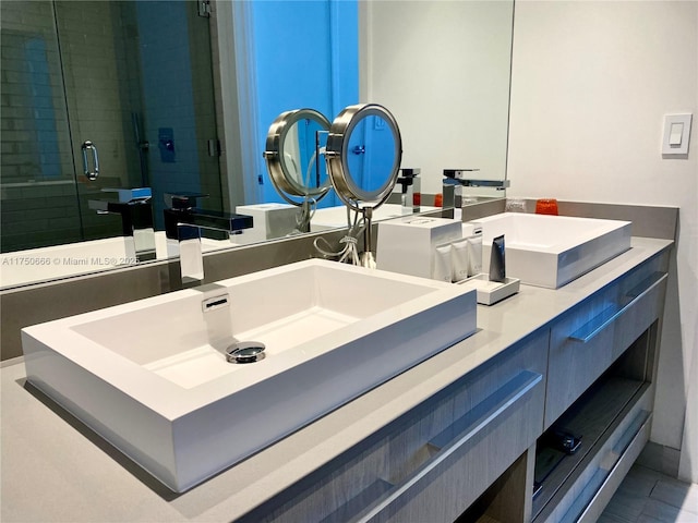 full bathroom featuring a sink, a shower stall, and double vanity