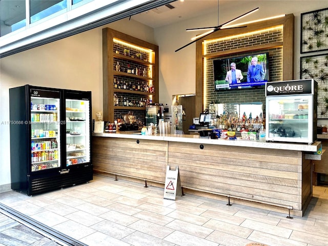 bar featuring a bar and refrigerator with glass door