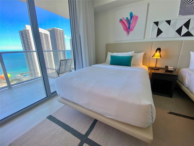 bedroom featuring a water view, expansive windows, and a view of city