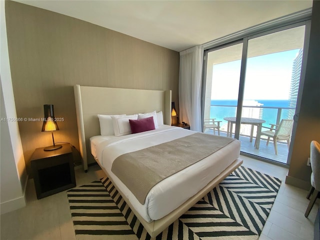 bedroom featuring a wall of windows, access to outside, and a water view