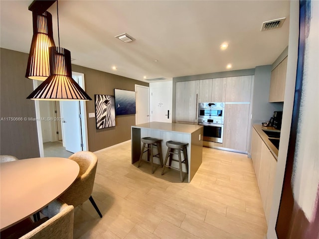 kitchen featuring stainless steel double oven, visible vents, light countertops, a center island, and modern cabinets