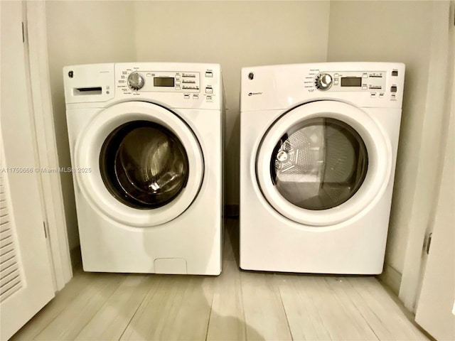 washroom with laundry area, light wood finished floors, and washing machine and clothes dryer