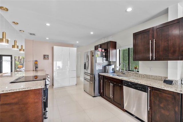 kitchen featuring decorative light fixtures, visible vents, appliances with stainless steel finishes, a sink, and light stone countertops