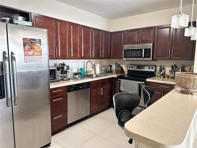 kitchen featuring decorative light fixtures, stainless steel appliances, light countertops, light tile patterned flooring, and a sink