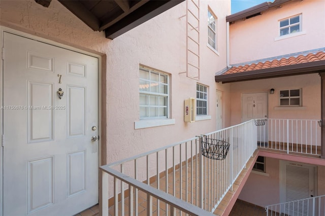 doorway to property featuring covered porch, a tiled roof, and stucco siding