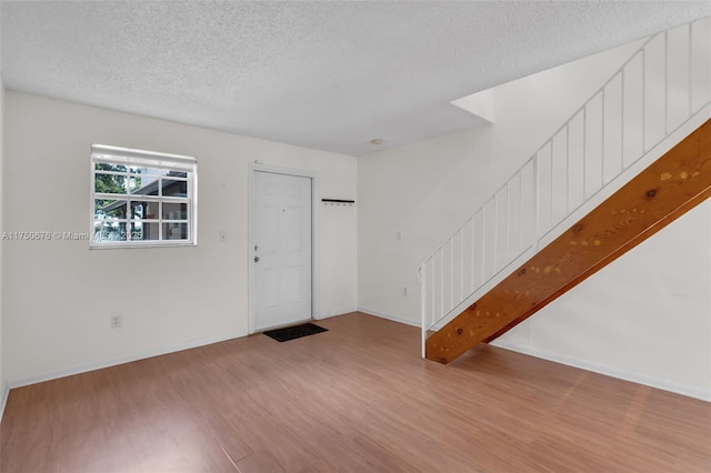 interior space featuring light wood-style floors, a textured ceiling, and baseboards