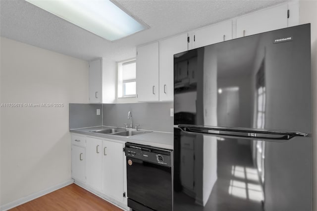 kitchen featuring white cabinets, light countertops, a textured ceiling, black appliances, and a sink