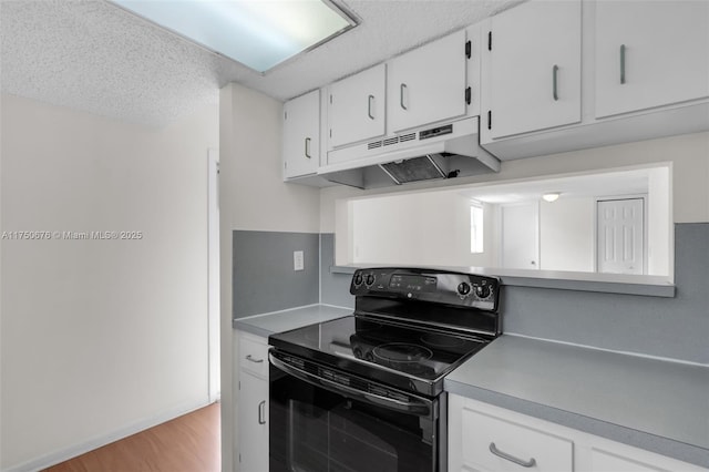 kitchen featuring black electric range, under cabinet range hood, white cabinetry, and light countertops