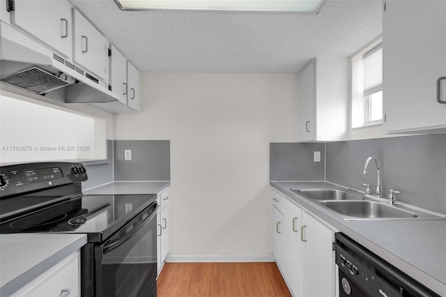 kitchen with light countertops, light wood-style flooring, white cabinets, a sink, and black appliances