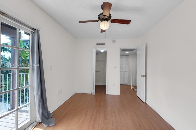 unfurnished bedroom featuring light wood-type flooring, a walk in closet, visible vents, and baseboards