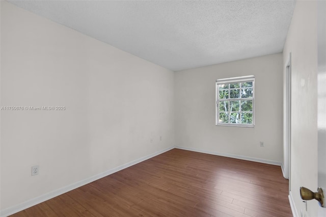 empty room featuring baseboards, dark wood finished floors, and a textured ceiling