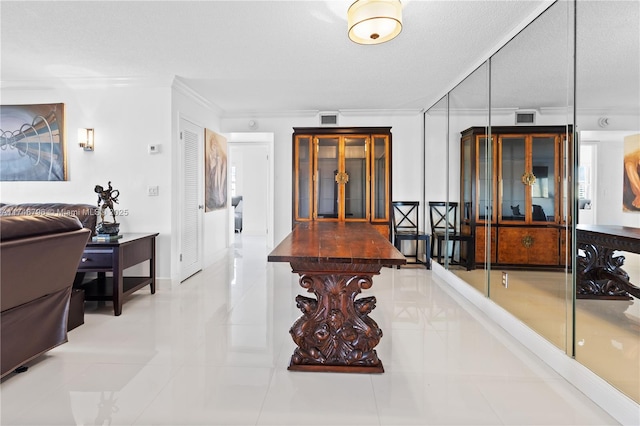 hallway with a textured ceiling, visible vents, and crown molding