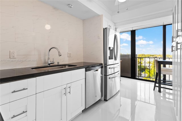 kitchen with tasteful backsplash, appliances with stainless steel finishes, ornamental molding, white cabinetry, and a sink