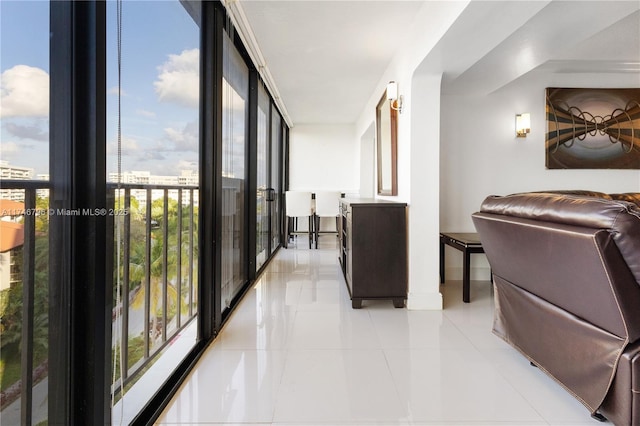 hallway with floor to ceiling windows, baseboards, and light tile patterned floors