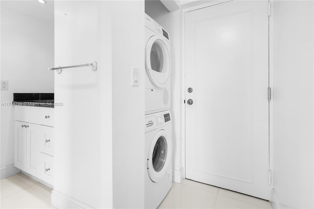 washroom with stacked washer and dryer, laundry area, and light tile patterned flooring