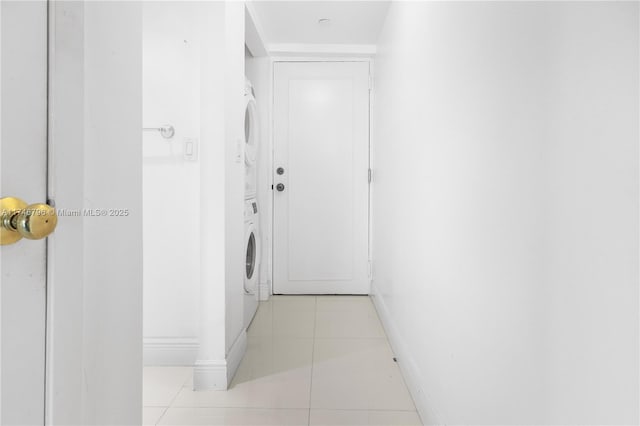 washroom with laundry area, stacked washing maching and dryer, light tile patterned flooring, and baseboards