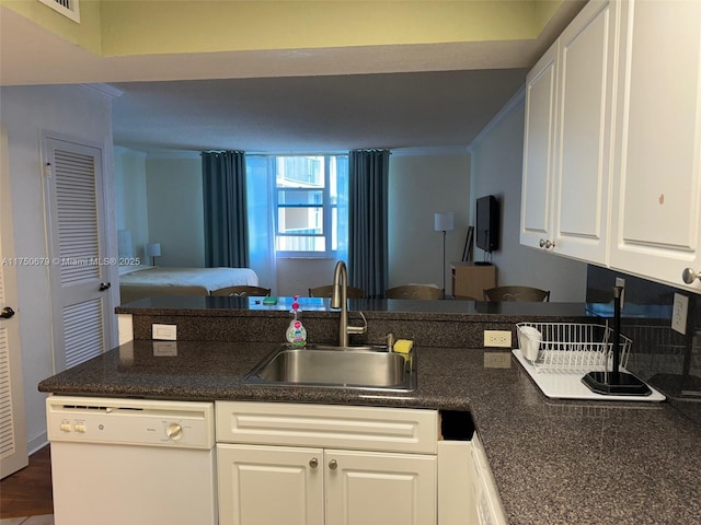 kitchen with dark countertops, ornamental molding, white cabinetry, a sink, and dishwasher