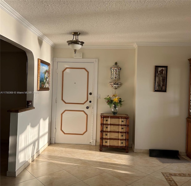 doorway to outside with light tile patterned floors, a textured ceiling, and crown molding