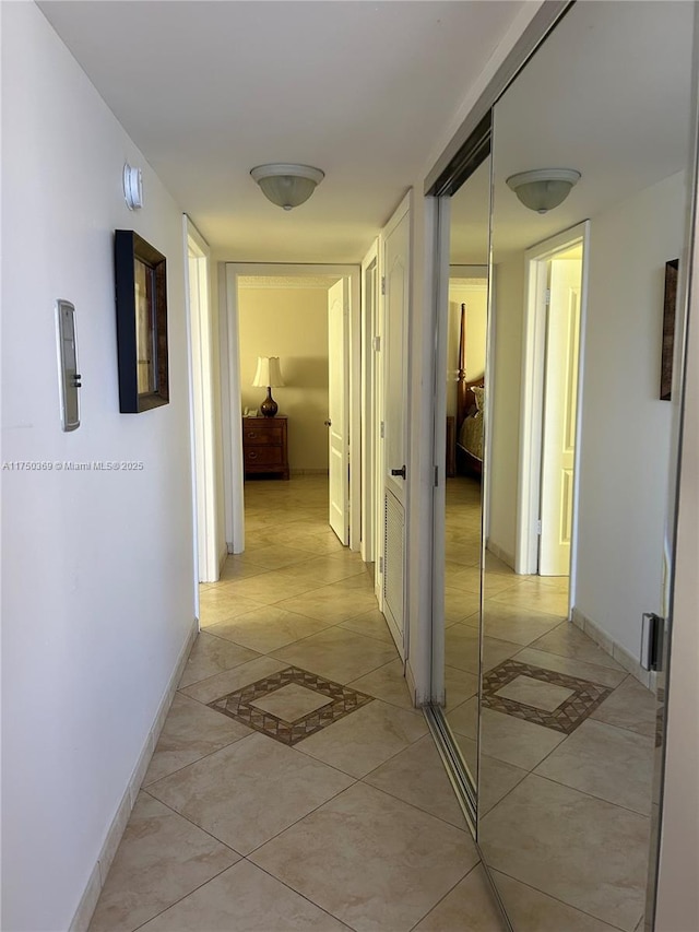 hall with light tile patterned flooring and baseboards