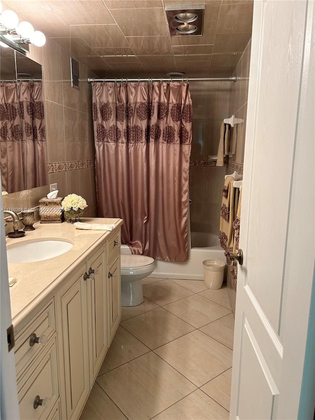 bathroom featuring toilet, shower / tub combo with curtain, tile patterned flooring, vanity, and tile walls